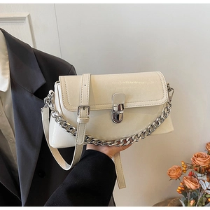 Detail of cream glossy shoulder bag with silver rotary lock and chunky metal chain strap