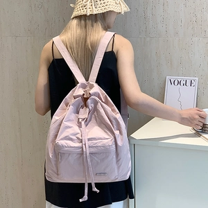 Minimalist light pink nylon drawstring backpack for women featuring a front zipper pocket