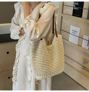 Detail of hand-woven off-white straw tote bag with brown leather straps and mesh pattern
