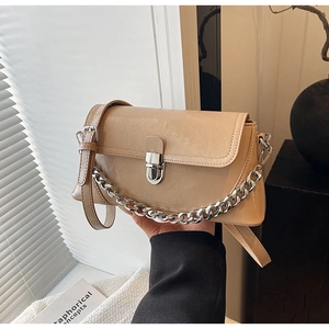 Detailed macro view of beige PU leather bag with silver metal twist lock and chain strap
