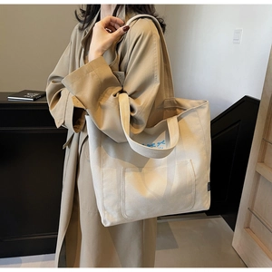 Canvas tote bag with blue bow print shown on model wearing a khaki trench coat