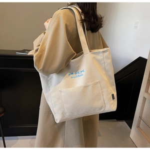 Detail of canvas tote bag featuring blue bow print and front pocket on shoulder strap