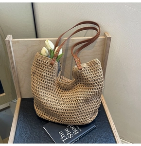 Detail der hohl gewebten Stroh-Tote-Bag mit braunen Ledergriffen und goldenen Metallnieten