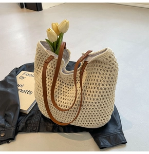 Detail der gewebten Strohtasche mit braunen Kunstlederriemen und Blumendekor