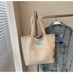 Detail of canvas tote bag with blue bow patterns and spacious front pocket
