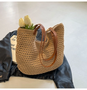 Detail der geflochtenen Strohtasche mit braunem Lederriemen und Nieten-Details