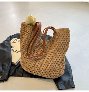 Close-up of handmade straw tote bag with brown leather straps and crochet hollow design
