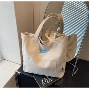 Detail of canvas tote bag featuring blue bow print and convenient front pocket design