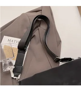 Detail of adjustable black woven shoulder strap with silver metal hooks on a blazer
