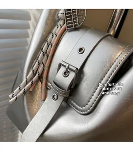 Détail du sac argenté en similicuir à texture plissée avec petit pendentif boulier