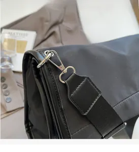 Detailed close-up of glossy nylon fabric and polished silver hardware on black tote bag