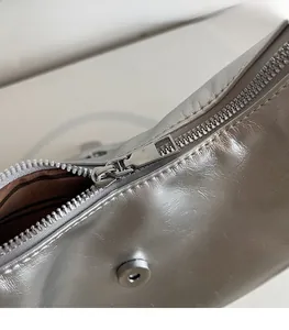 Détail d'un sac cabas argenté avec fermeture éclair en métal fluide et boucle magnétique