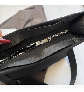 Macro detail of a smooth silver metal zipper on a black commuter tote handbag