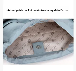 Détail de la poche intérieure avec bouton pression d'un sac à bandoulière bleu clair