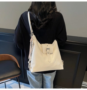 Vue arrière d'un grand sac fourre-tout blanc brillant porté avec un charme tressé