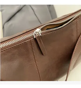 Macro shot of smooth silver metal zipper and fine stitching on dark brown leather bag
