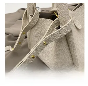 Macro view of creamy white lychee grain leather bucket bag with gold stud hardware details
