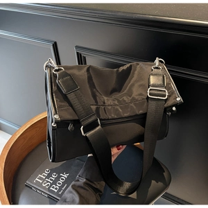 Detail of black nylon crossbody bag with wide shoulder strap and silver metal hardware