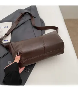 Detailed view of the dark brown leather crossbody bag with visible stitching and texture