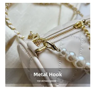Macro detail of quilted cream leather bag with golden hardware and pearl chain strap