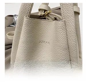 Detail of cream pebbled leather bucket bag with embossed logo and gold metal hardware