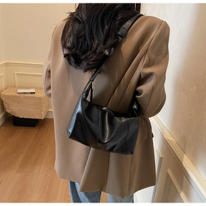Detail of minimalist black crescent dumpling bag showing soft leather texture and wide strap