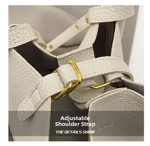 Close-up of cream leather bucket bag showing adjustable gold buckle and fine grain texture