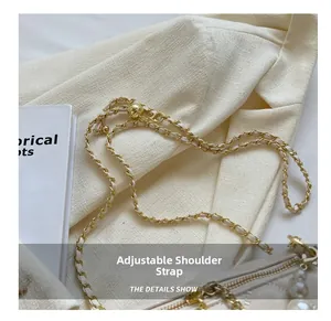 Close-up of adjustable chain shoulder strap on beige quilted crossbody bag with pearl charm