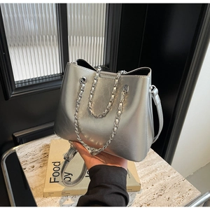 Detailansicht der hochglänzenden silbernen Beuteltasche mit Kettenriemen und Metalltextur