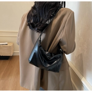 Detail of black faux leather hobo bag with natural folds and sleek metal zipper closure