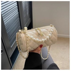 Detailed view of cream quilted cylinder bag with pearl handle and star charm