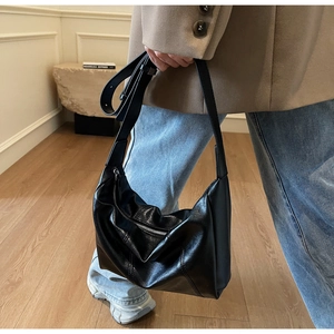 Side view of elegant black soft leather hobo shoulder bag shown on a model in a minimal studio