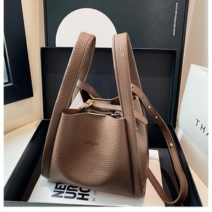 Detail of dark brown bucket bag in pebbled leather with gold hardware and shoulder strap