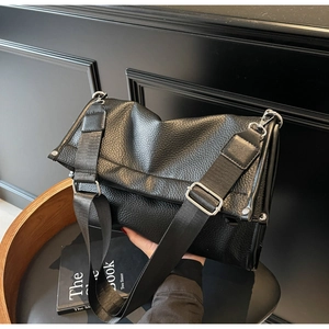 Close-up of black lychee grain leather handbag with wide nylon shoulder strap