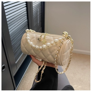 Detail of beige quilted cylinder bag with pearl handle and star pendant chain