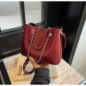 Detail der weinroten Lackledertasche mit silbernen Metallketten und verstellbarem Tragegurt