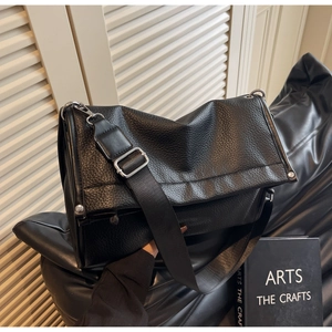 Close-up of black litchi pattern leather tote bag with silver metal buckle and wide strap