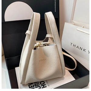 Detailed view of cream leather bucket bag with UZBAG logo and metallic hardware