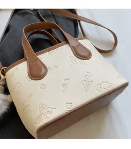 Detailed side view of embossed leather bucket bag with contrasting brown base and handle
