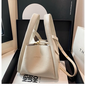 Detail of white lychee leather bucket bag with gold hardware and UZBAG logo