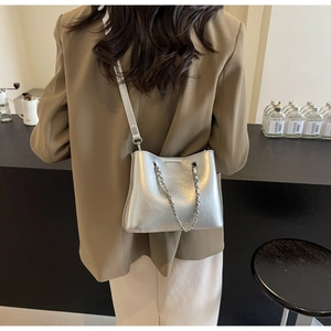 Silberne Umhängetasche mit Kette, präsentiert von einem Modell im Business-Anzug