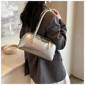 Silver metallic baguette bag with pleated texture and shoulder strap on model