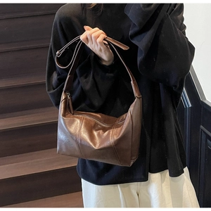 Detail view of a vintage dark brown leather shoulder bag with an adjustable strap