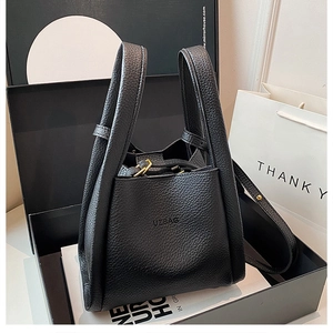 Close-up of black lychee grain leather bucket bag with metallic lock and UZBAG logo