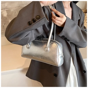 Close-up of metallic silver shoulder bag featuring unique pleated texture and zipper