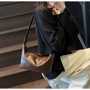 Detail view of a vintage dark brown leather shoulder bag shown on a model