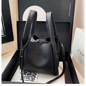 Close-up of black lychee grain leather bucket bag with UZBAG logo in a gift box