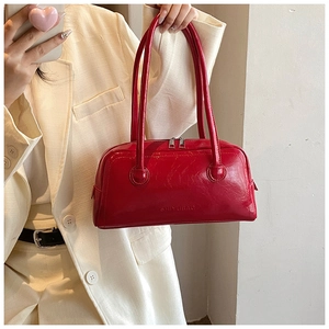 Detail of red glossy leather Boston bag showing silver zippers and brand logo