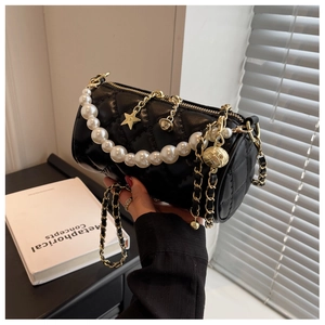 Detail of black quilted barrel bag with white pearls and gold chain strap decoration