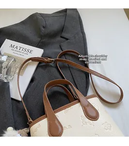 Detail of embossed floral patterns on cream leather bucket bag with adjustable brown strap